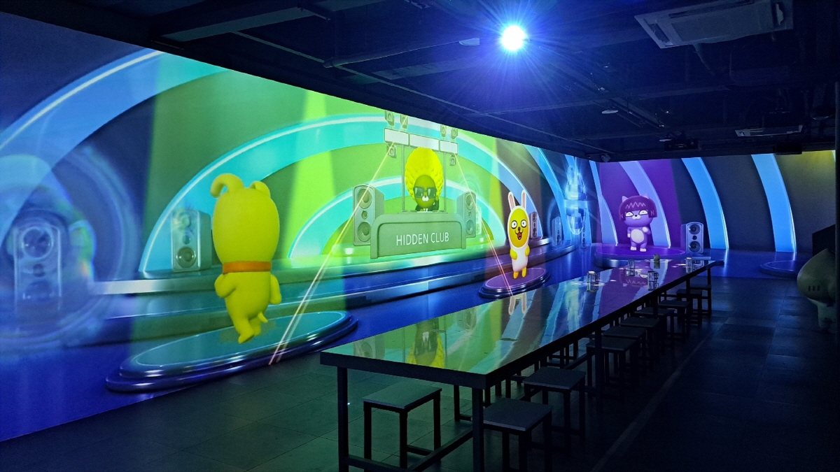 Theme park space with character video projected on curved walls and tables